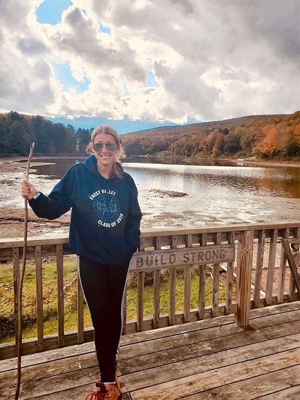 A woman standing on a wooden bridge with a stick.