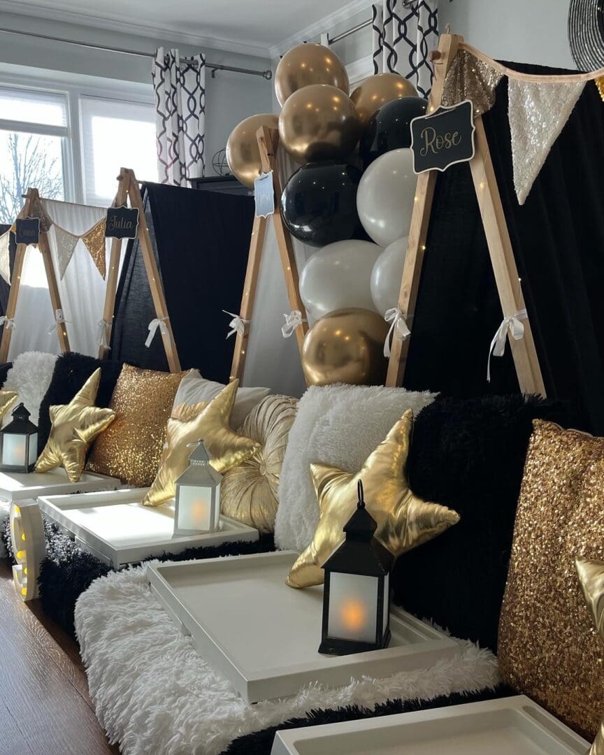 A black and gold birthday party with balloons and pillows.