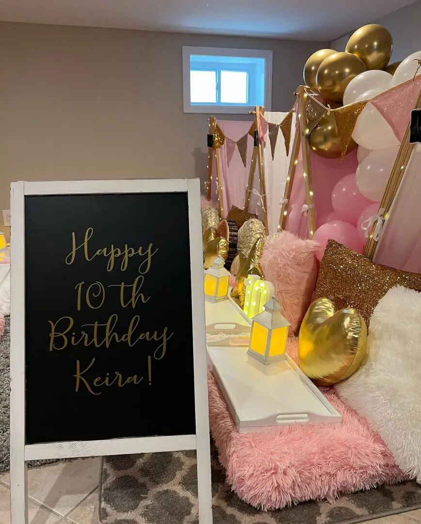 A pink and gold birthday party with balloons and a sign.
