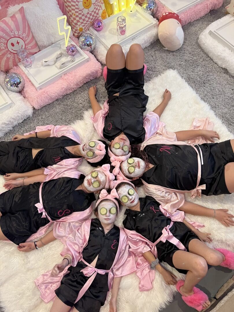 A group of girls in pink robes laying on a rug.