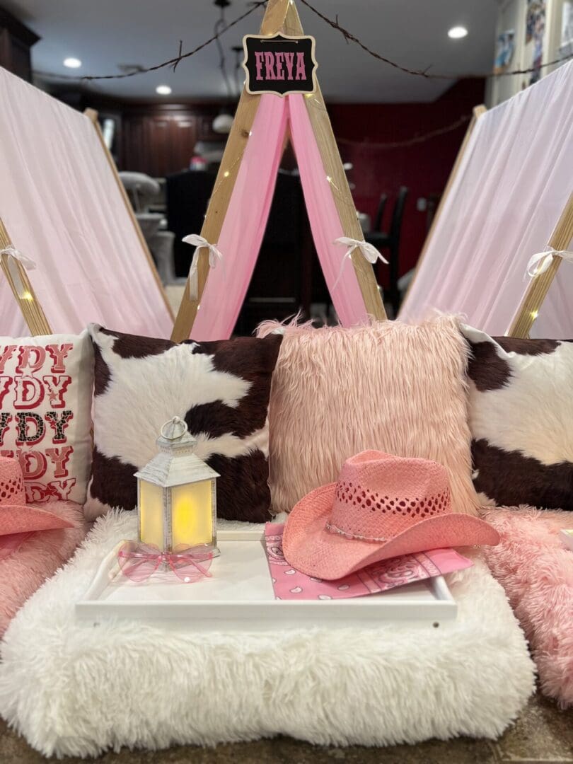 A pink teepee with pink pillows and a cowboy hat.