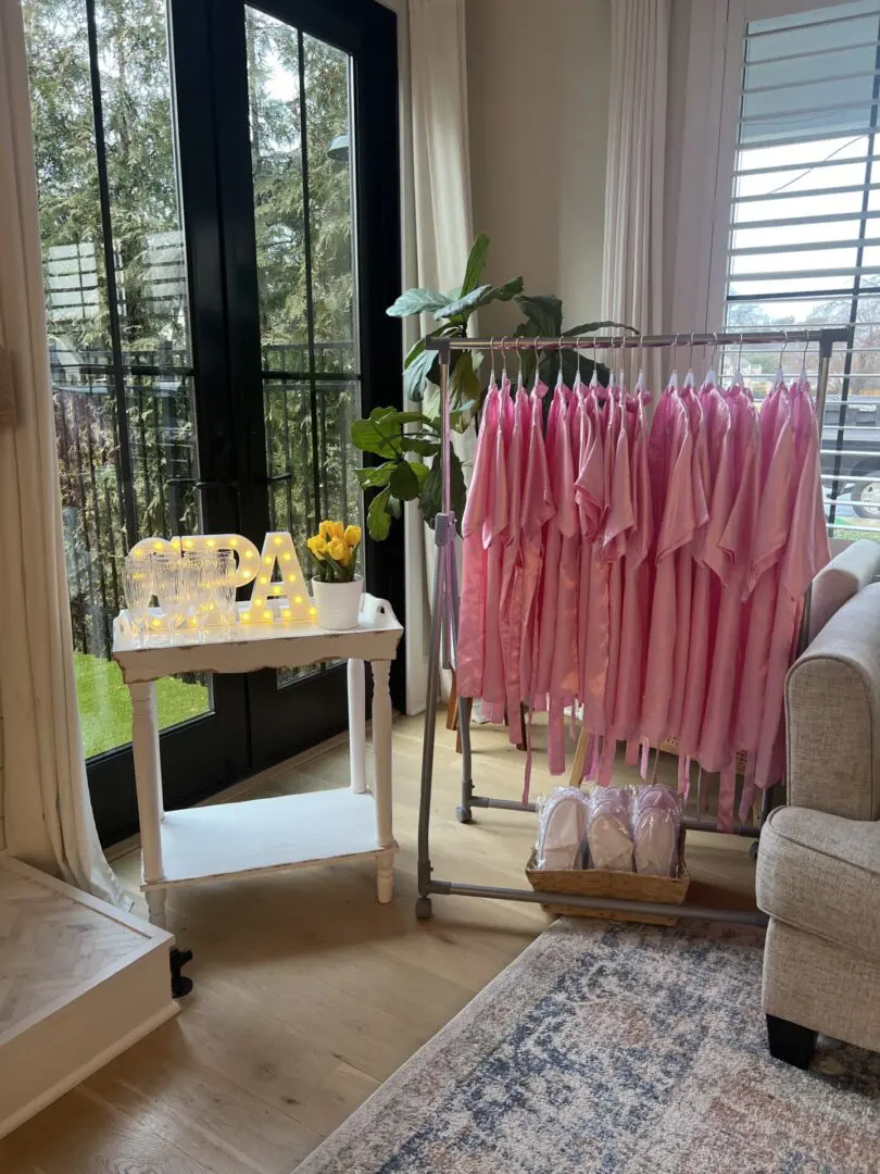 Pink robes hanging on a rack in a living room.