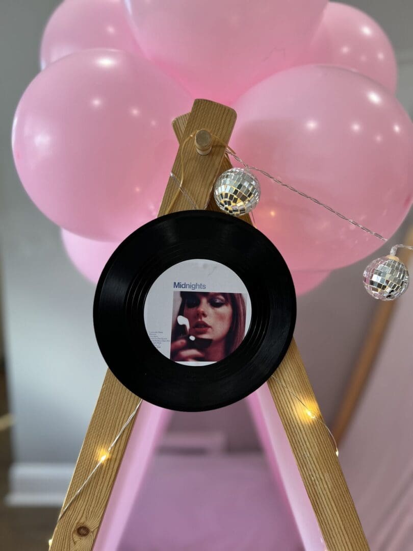 A pink teepee decorated with balloons and a record.